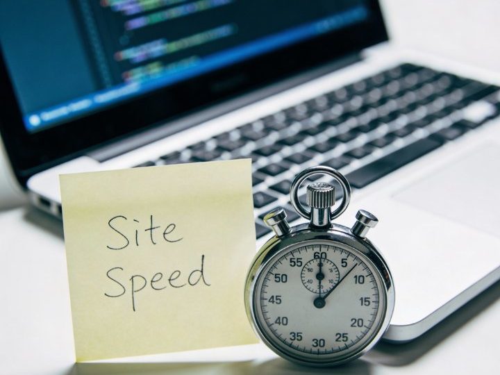Laptop mit Code, gelbes "Site Speed"-Post-it und Stoppuhr neben dem Bildschirm