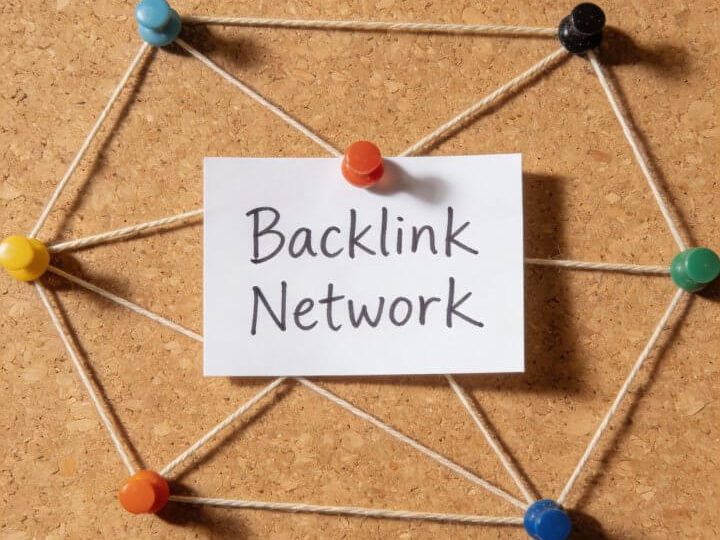Bunte Pushpins verbinden "Backlink Network"-Notiz auf Korkbrett